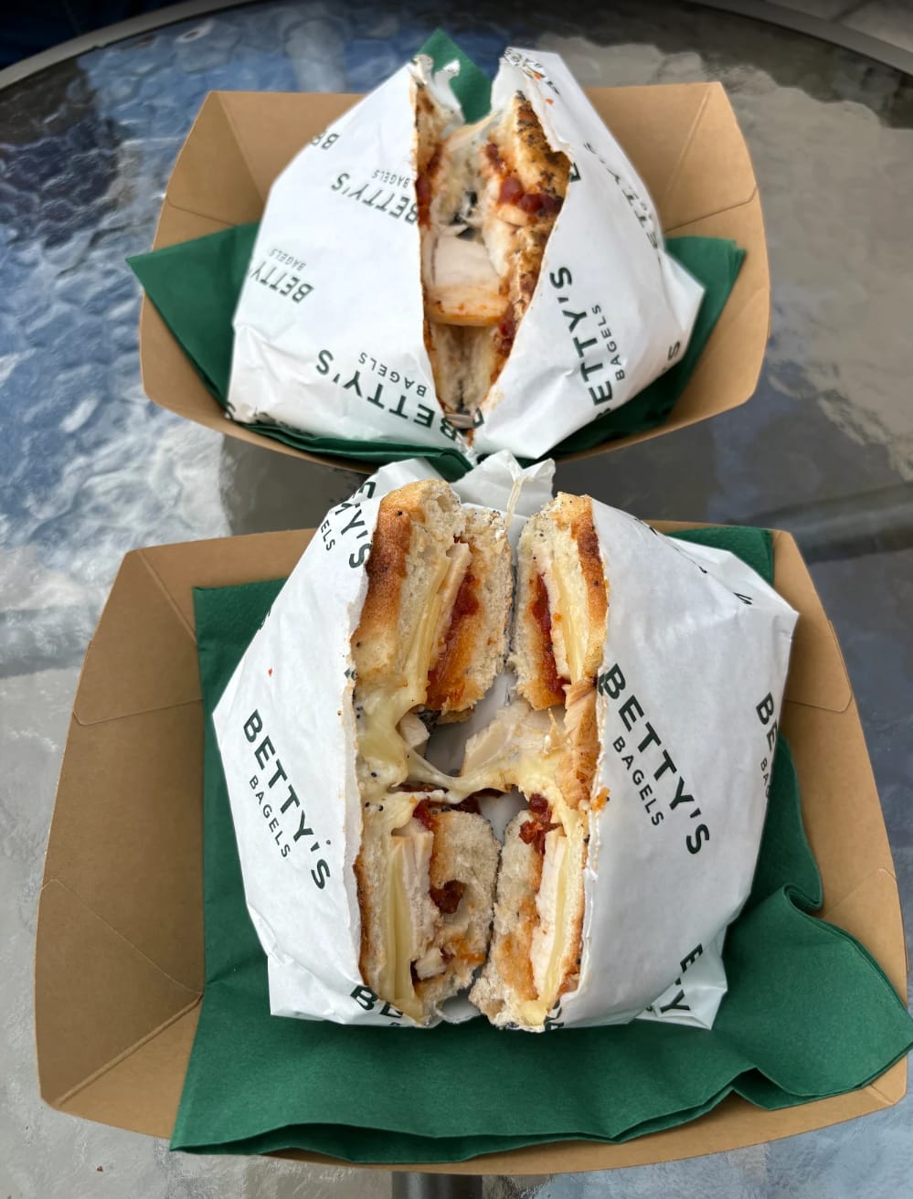 Two Chuffin' El Chicken bagels in branded Betty's Bagels wraps, in kraft trays